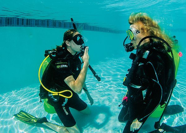 [ONE] After indicating that she is out of air, this diver signals that she needs to share air.